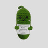 A handmade plush knitting doll shaped like a green pickle with a smiling face and an emotional support message tag.