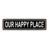 A rectangular vintage metal sign with distressed texture displaying the text OUR HAPPY PLACE in white capital letters.