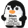 A black and white penguin crochet doll with a sign that reads Mom I Flippin Love You