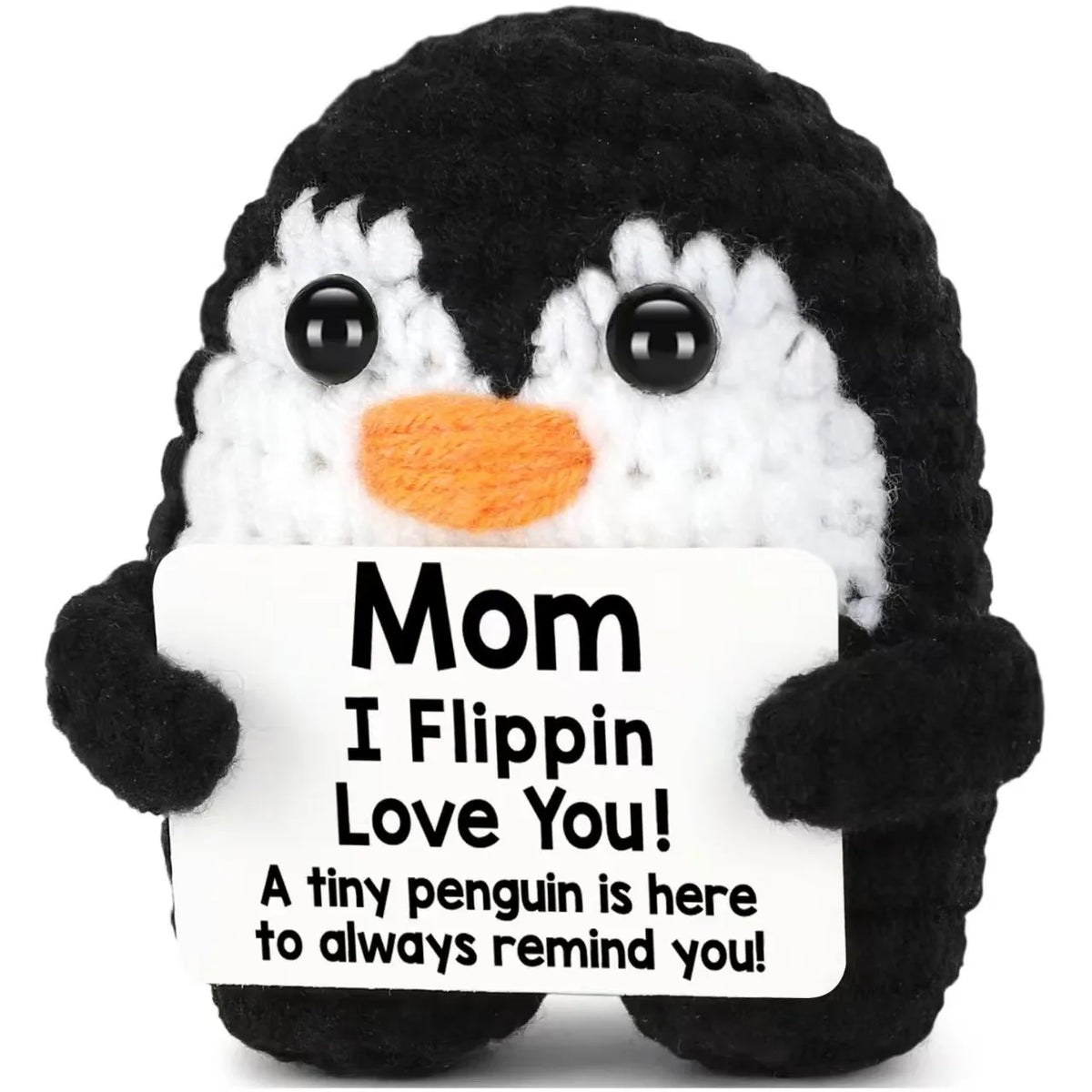 A black and white penguin crochet doll with a sign that reads Mom I Flippin Love You
