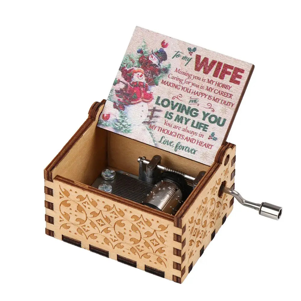 A vintage hand-cranked wooden music box with a lid featuring a handwritten message to wife