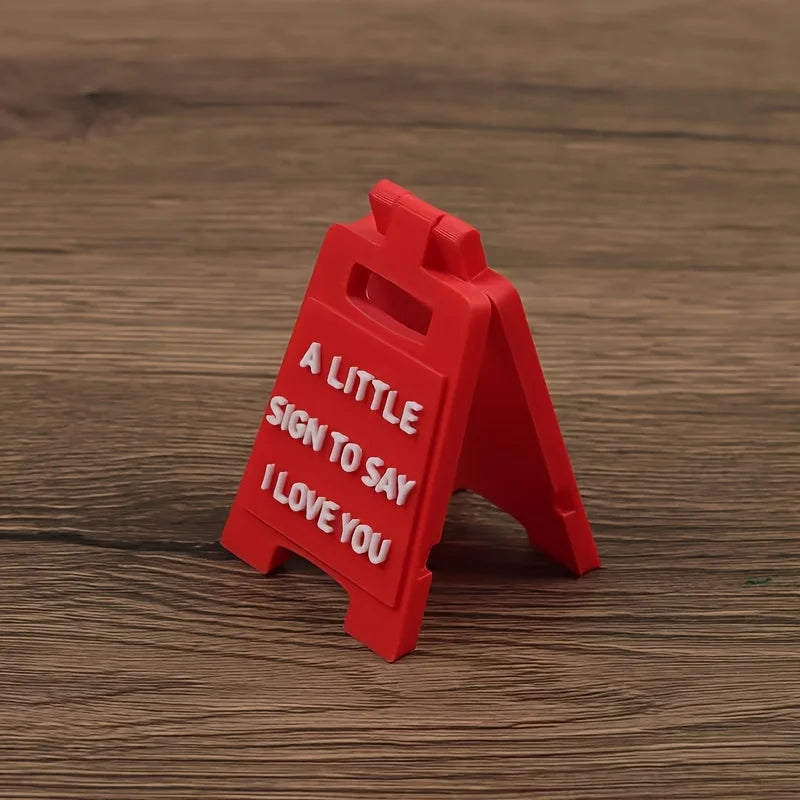 A red wooden sign shaped like an arrow with the text A LITTLE SIGN TO SAY I LOVE YOU engraved on it.
