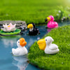 Petites sculptures d'animaux en résine : flamant rose et canard blanc sur une surface verte texturée.