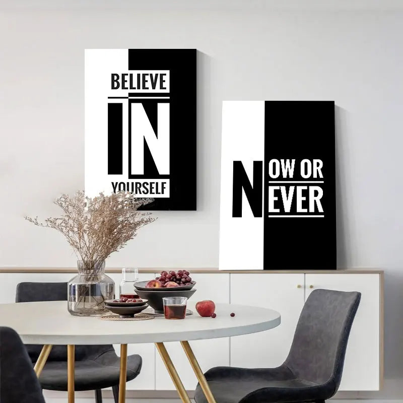 A set of black and white inspirational quote canvas art posters displayed on a white shelf with a table and chair.