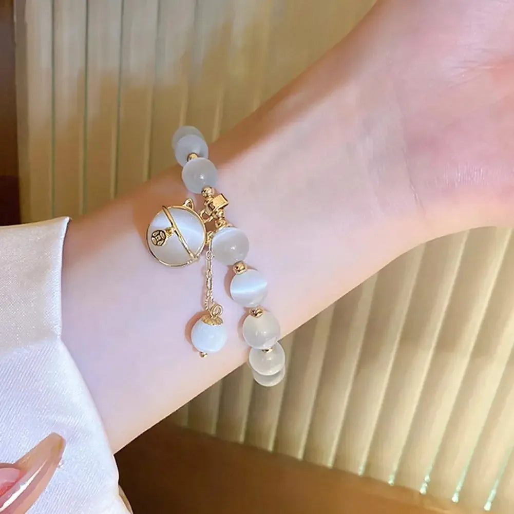 A close-up shot of a natural stone lily of the valley bracelet with white and pale blue beads on a wrist.