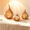 Three handcrafted wooden lotus candle holders casting warm light on a draped table.
