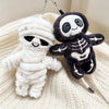A white mummy skeleton plush keychain hanging from a silver chain, next to a dark gray version.