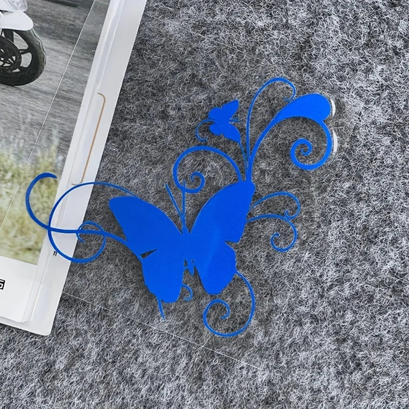 A bright blue vinyl butterfly decal with swirling lines is placed on a gray, textured surface.