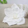 A large white PE foam rose flower displayed on a beige sofa next to white lace fabric.