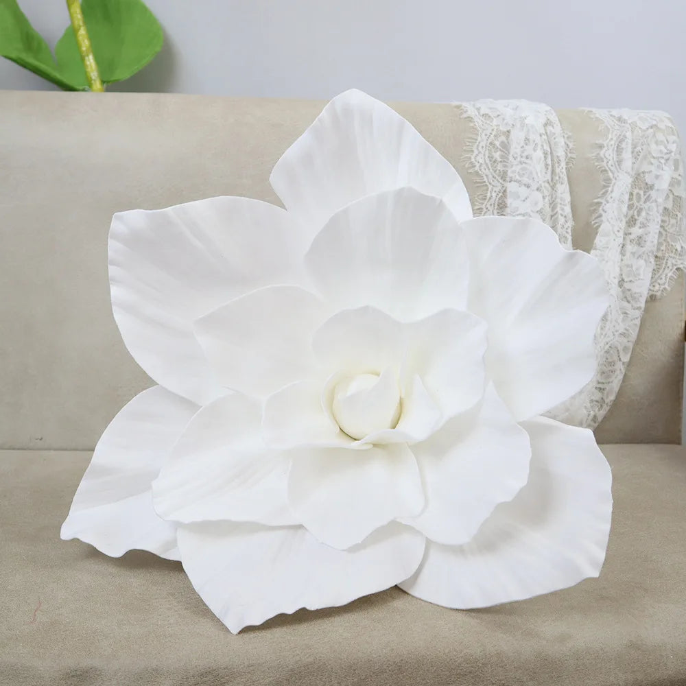 A large white PE foam rose flower displayed on a beige sofa next to white lace fabric.