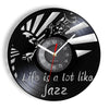 A black vinyl record wall clock with a white face and silver markings, showing the time.