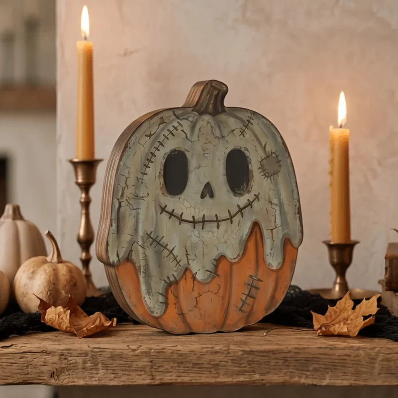 A carved pumpkin decoration sits on a wooden surface next to lit candles and autumn leaves.