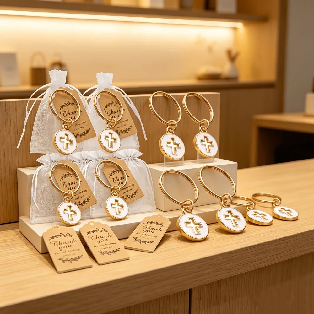 Gold cross keychains with thank you cards and organza bags displayed on a wooden surface.
