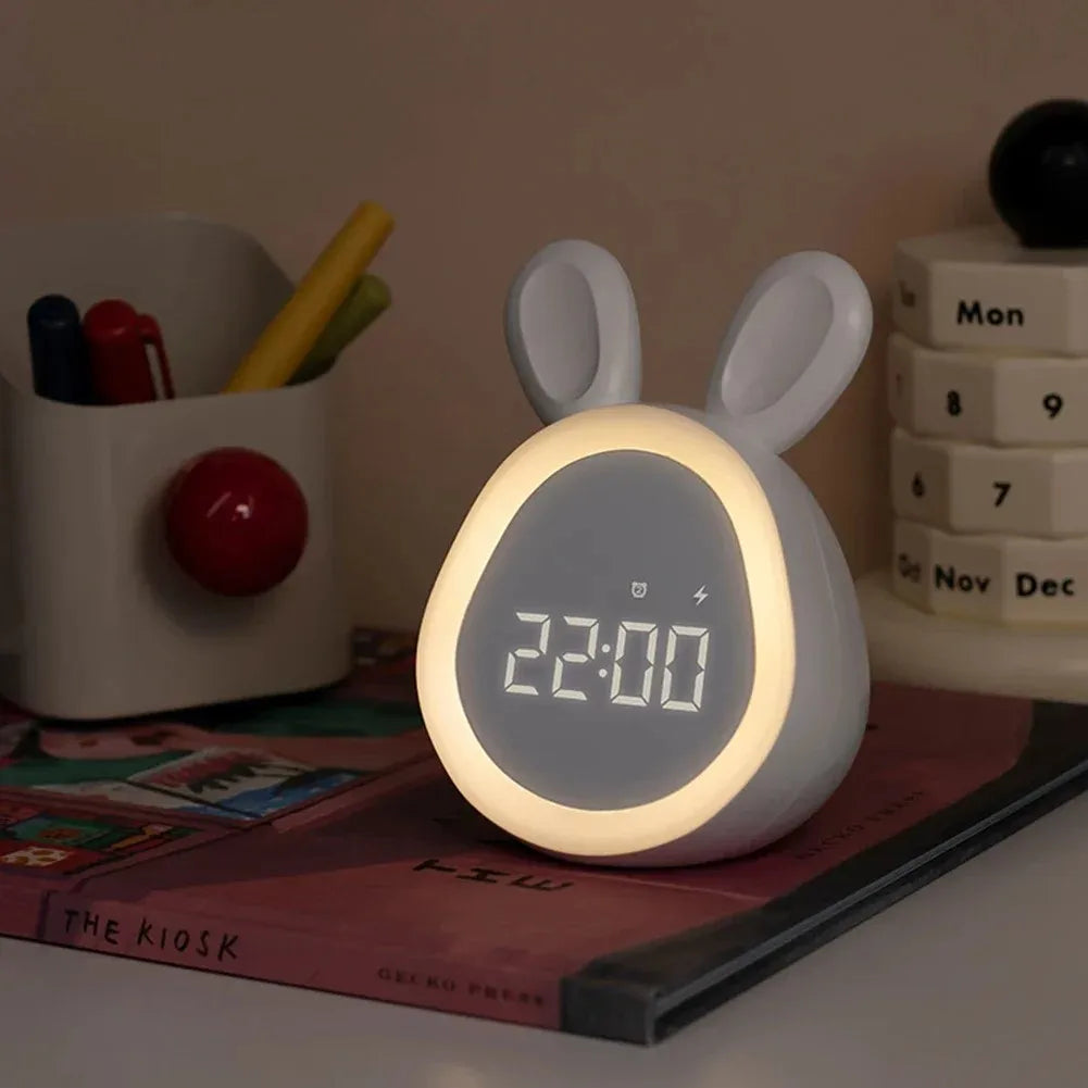 A white mini LED cartoon rabbit alarm clock night light with a glowing face displaying 22:00 on a wooden surface.