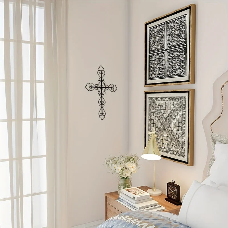 A framed metal cross and geometric pattern wall decor displayed on a light-colored wall next to a window.