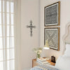 A framed metal cross and a geometric pattern artwork displayed on a wall next to a window.