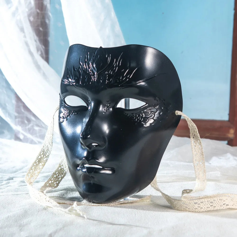 A black face mask with intricate, textured details is displayed on white fabric.
