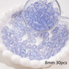 A clear glass dropper shows purple blue spacer beads scattered on a white dish.