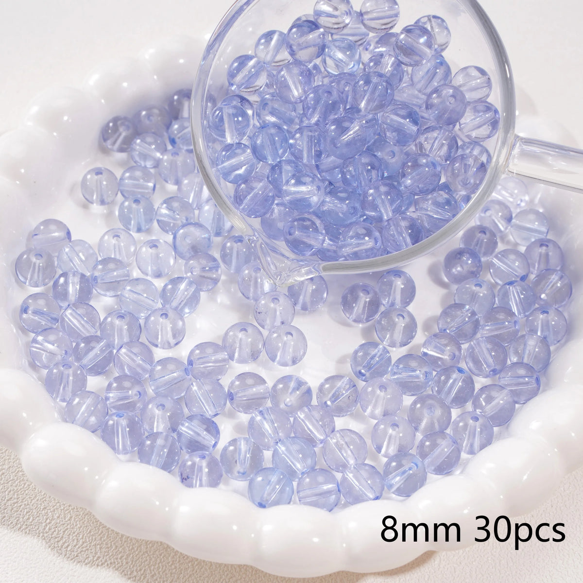 A clear glass dropper shows purple blue spacer beads scattered on a white dish.
