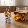 A small Yorkshire Terrier acrylic pendant necklace resting on a wooden table next to crumpled brown paper.