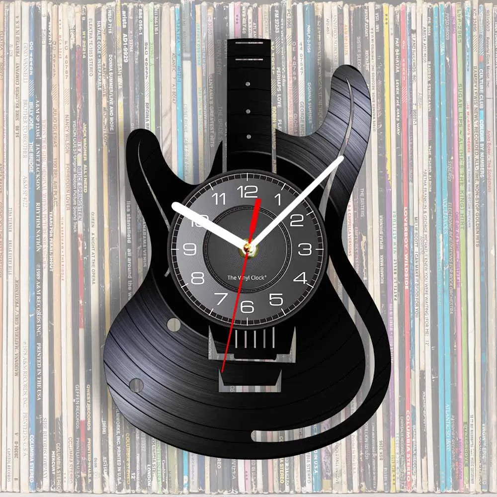 A black guitar-shaped wall clock with a vinyl record face and hands, set against a background of stacked vinyl records.