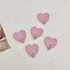 A set of five pink heart-shaped adhesive hooks for use in various rooms.
