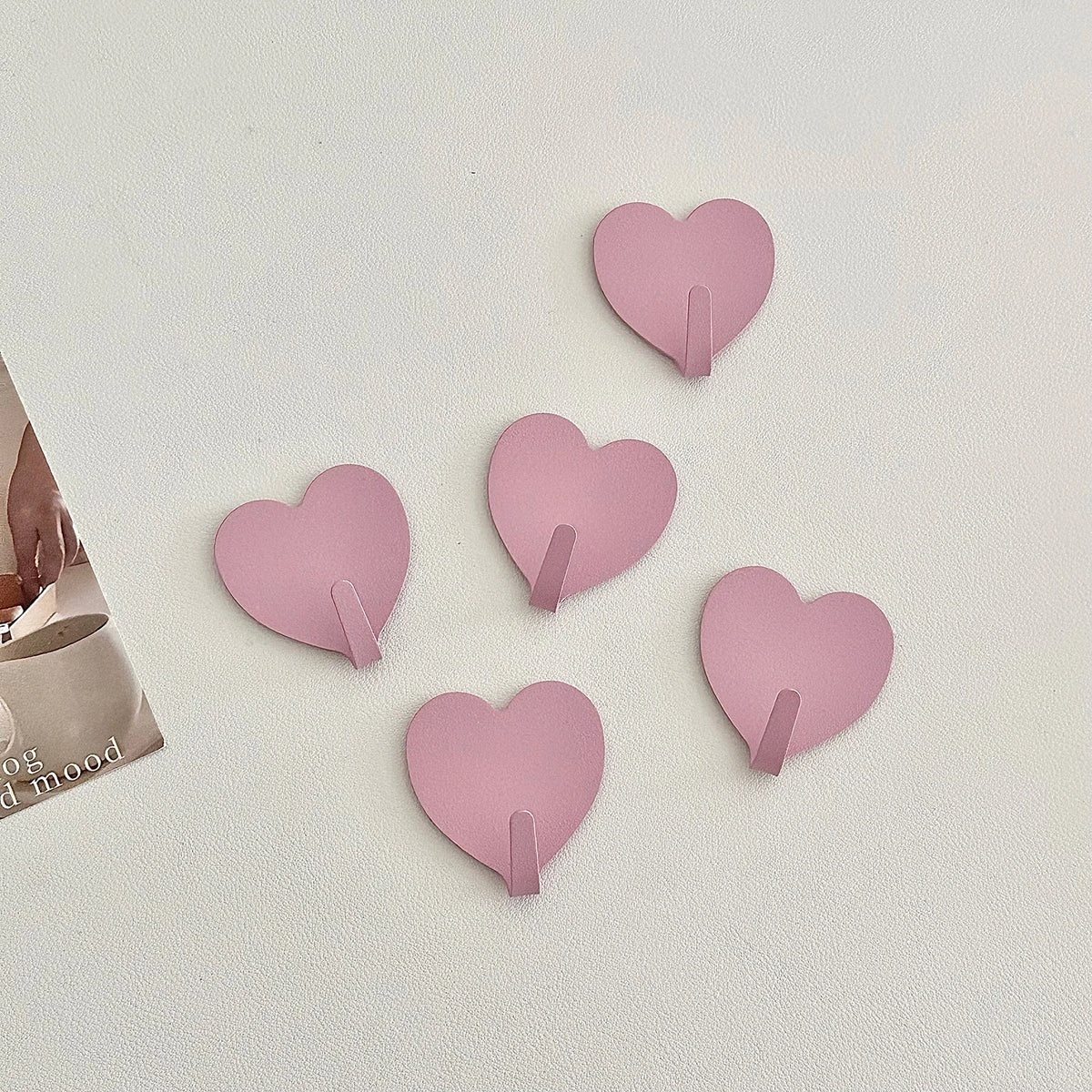 A set of five pink heart-shaped adhesive hooks for use in various rooms.