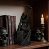 A black gothic female grim reaper figurine holding a scythe displayed on a wooden shelf.