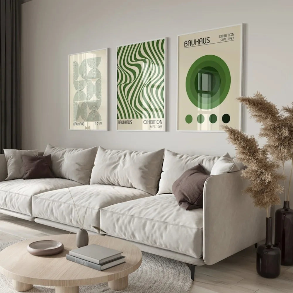 A modern living room featuring a light sofa and three framed Bauhaus art prints on the wall.