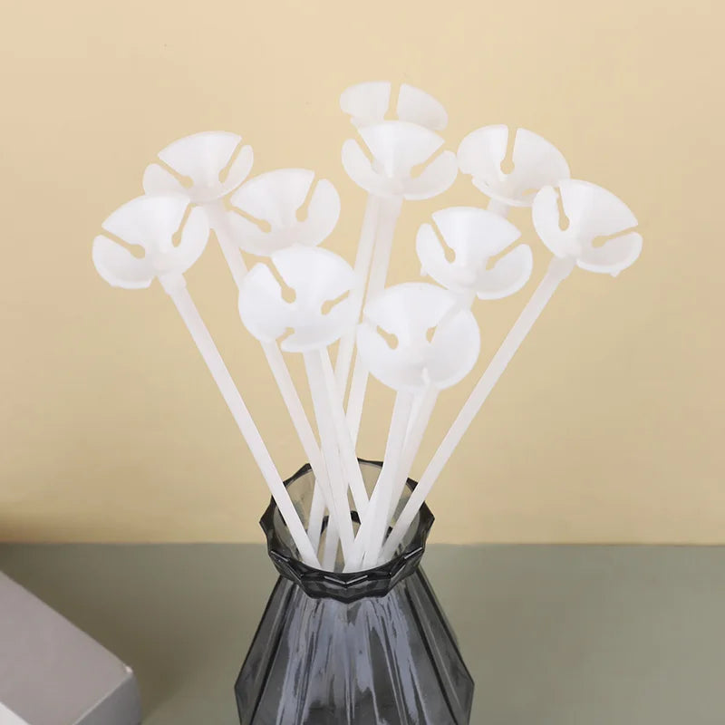 White macaron balloon sticks with holder cups arranged in a dark glass vase for party decor