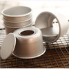 A set of five light gray non-stick round cake molds with removable bases resting on a wire rack.