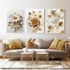 Tres impresiones en lienzo enmarcadas con diseños florales de girasoles dorados y blancos, exhibidas en un sofá gris claro.