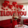 A display of red foil balloons shaped like letters and hearts spelling out I LOVE YOU, set against a bright room with red fur