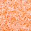 Close-up view of small, translucent orange glass rice beads for jewelry making