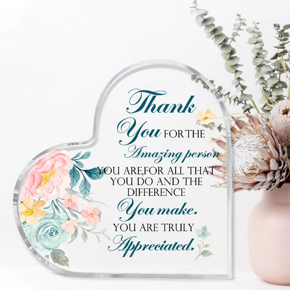 A clear acrylic heart-shaped thank you sign with elegant script text and floral accents