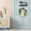 Decorative metal key hooks for wall organization featuring a black silhouette of a tree and various figures on a light gray d