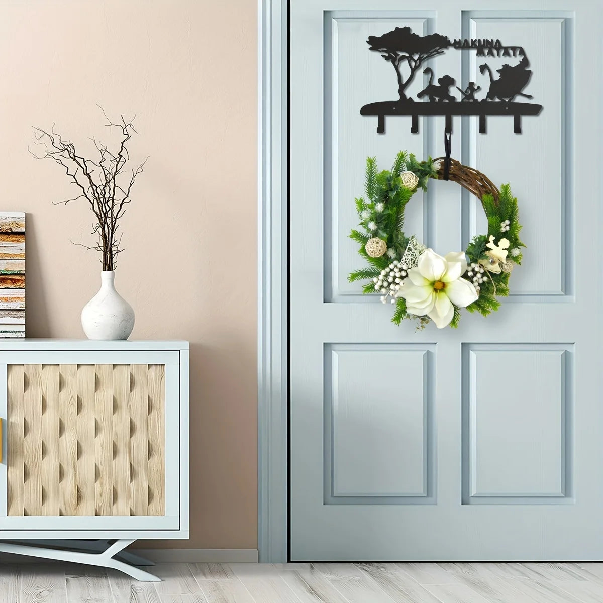 Decorative metal key hooks for wall organization featuring a black silhouette of a tree and various figures on a light gray d