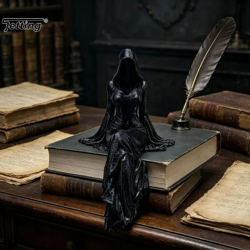 Schwarze Harzstatue einer weiblichen Figur in fließendem Gewand mit Kapuze sitzt auf einem alten Buch umgeben von ledergebund