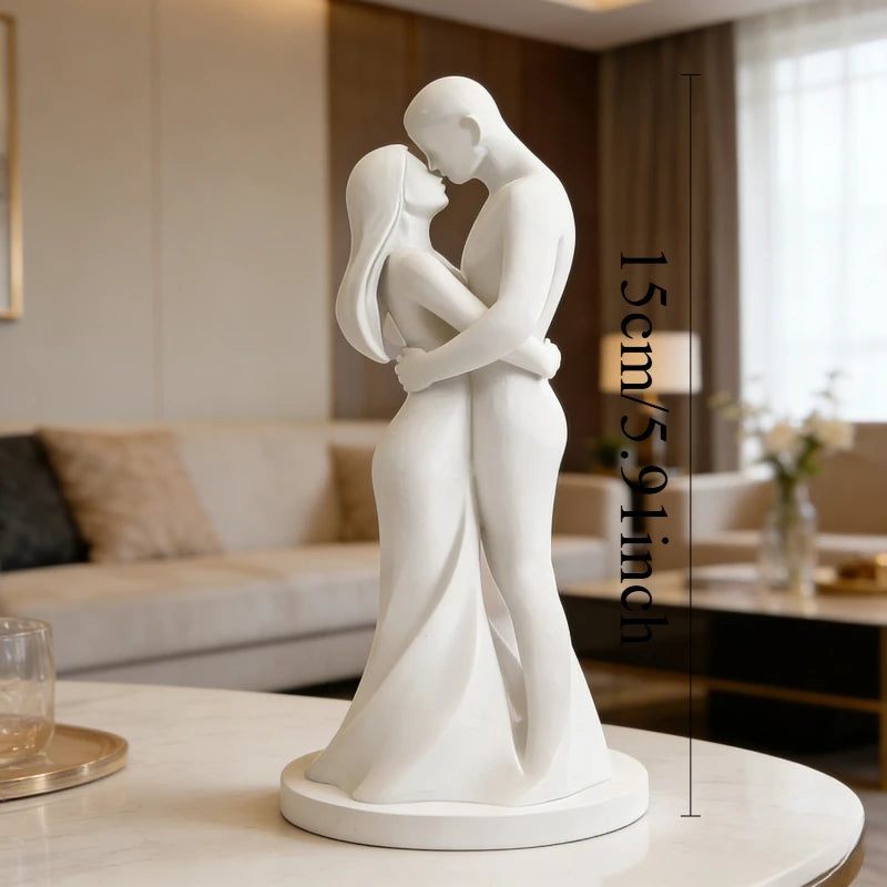 A white minimalist sculpture of a couple embracing, displayed on a table.