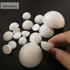 A hand holds several white polystyrene foam balls for crafting and decorating on a dark surface.