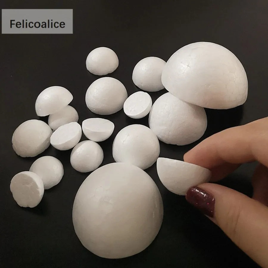 A hand holds several white polystyrene foam balls for crafting and decorating on a dark surface.
