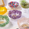A collection of colorful natural crystal lotus bowls in various shades including yellow, purple, and green, displayed on a wh