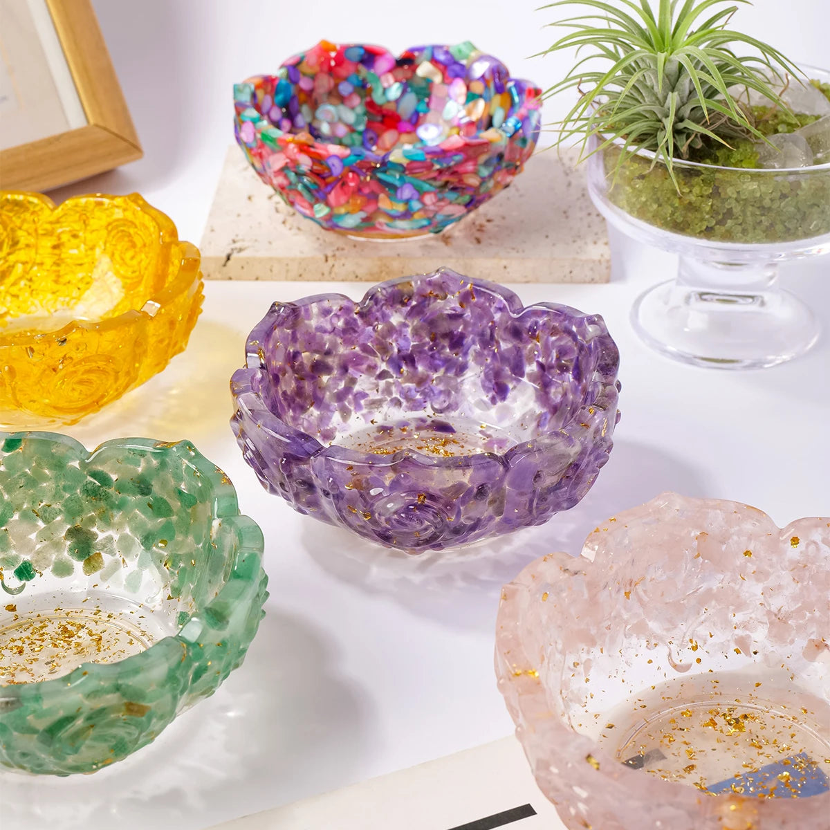 A collection of colorful natural crystal lotus bowls in various shades including yellow, purple, and green, displayed on a wh