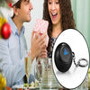 A woman is laughing while holding a black Magic 8 Ball keychain, with a man looking at her in the background.