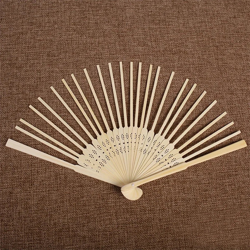Ventilateur à main squelette en bambou pliable de bois clair avec ailettes rayonnantes sur fond de tissu brun.