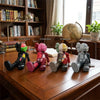 A set of five colorful Kawaii bear figurines in various poses displayed on a wooden desk.
