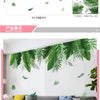 Green tropical leaf wall stickers displayed hanging on a white wall above a gray sofa.