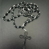 A black beaded rosary necklace featuring a medallion and a cross pendant.