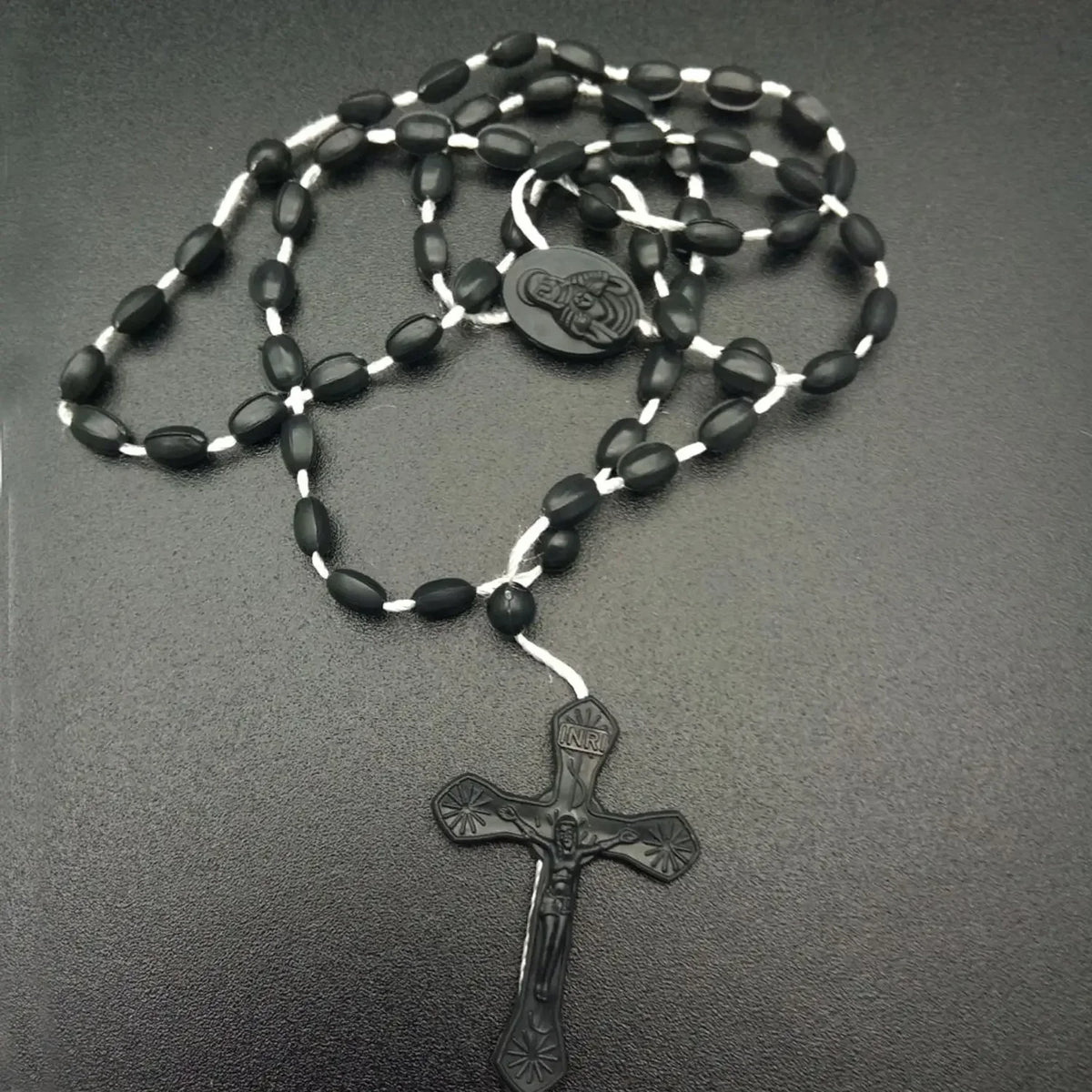 A black beaded rosary necklace featuring a medallion and a cross pendant.