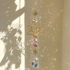 A hanging lotus flower crystal glass suncatcher with prism beads catching light in a bright room.